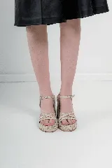 Sandalias de tacón alto y plataforma, color negro, con capellada de tiras cruzadas y cierre de hebilla en el tobillo. Cuentan con textura grabada en todo su diseño.