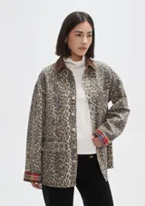 Campera de jean con estampado animal print, cuello de pana en color marrón, cierre frontal con botones metálicos, bolsillos frontales con solapa y puños con detalle de tela escocesa en tonos rojos y azules.