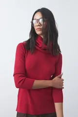 Polera de cuello alto holgado, manga larga y diseño de tejido fino con aberturas laterales en el ruedo.