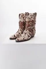 Bota de cuero color marrón con puntera fina y taco bajo. Presenta correas de cuero negro con apliques metálicos plateados.