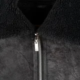 Campera de gamuza sintética color negro, completamente forrada en corderito. Presenta cierre frontal metálico, cuello solapa, puños y bolsillos frontales con detalles en corderito.