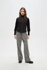 Chaleco negro con diseño capitoneado, cierre frontal con botones a presión y cuello alto.