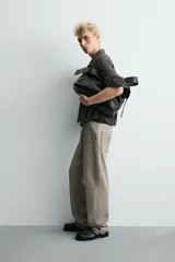 Pantalón de corte relajado confeccionado en tejido de algodón con efecto lavado. Presenta diseño de cinco bolsillos, cierre frontal con cremallera y botón, y detalles de estampados a contraste en la parte delantera y trasera.