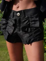 Short de lino negro con volados frontales decorativos, cierre frontal con botón y trabillas para cinturón.