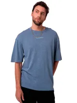 Remera de corte relajado color azul grisáceo, con cuello redondo y mangas cortas. Presenta un bordado sutil con el nombre de la marca en el pecho y un parche tejido en la manga.