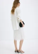 Camisa oversize blanca de mezcla de algodón y lyocell, con cuello camisero, manga larga, puños abotonados y detalle de perlas aplicadas en toda la prenda.