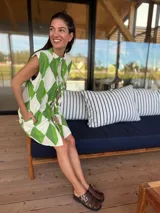 Vestido camisero sin mangas, corto, con cuello mao y lazos ajustables en el frente. Presenta un estampado geométrico de rombos en verde lima y blanco.