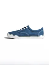 Championes de lona color azul grisáceo, estilo skate o casual, con cordones blancos y suela de goma blanca con una línea fina azul en el borde.