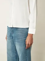 Camisa de manga larga con cuello clásico y cierre frontal de botones, confeccionada en tela con acabado satinado.