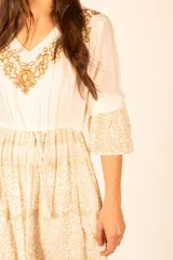 Vestido largo color crudo con bordado dorado en el escote y estampado cachemir en la falda.