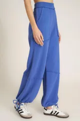 Pantalón de jogging azul de tejido de rizo suave con cintura alta elastizada, bolsillos laterales, costuras expuestas y lazo en el tobillo.
