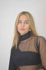 Vestido corto negro con cuello alto, mangas largas de tul y transparencias en el torso y abdomen.