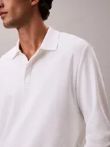 Chomba de manga larga Calvin Klein confeccionada en algodón interlock, con cuello clásico, cartera con botones y logo bordado en el pecho.