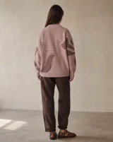 Buzo de punto amplio y relajado, color rosado con diseño floral en tonos marrones. Posee cuello redondo alto y terminaciones acanaladas en cuello, puños y ruedo.