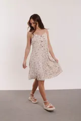 Vestido corto con estampado floral en tonos rosa, amarillo y azul. Tiene breteles finos, corte evasé y botones decorativos en el frente.