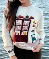 Sweater de punto color blanco marfil con diseño jacquard en el frente que representa una alacena con vajilla, detalles bordados a mano, cuello redondo y manga larga.
