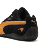 Championes Puma modelo Speedcat en colaboración con McLaren, color negro con detalles en naranja papaya. Diseño de perfil bajo inspirado en el automovilismo, confeccionado en gamuza con el logo de Puma y el emblema de McLaren en el lateral.