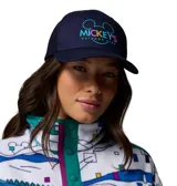 Gorra azul marino tipo trucker con red en la parte trasera, visera curva y estampa frontal de Mickey's Outdoor Club en colores turquesa, amarillo y rosado, en colaboración con Columbia y Disney.