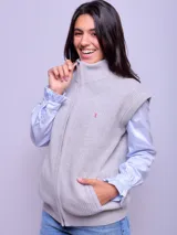 Chaleco de lana color crudo, con cierre frontal completo, cuello alto y bolsillos laterales. Presenta un diseño tejido con textura acanalada.
