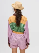 Short de corte boxy confeccionado en viscosa con estampado geométrico de estrellas en tonos rosados. Presenta una pretina elástica en color naranja y cordón de ajuste en color marrón.