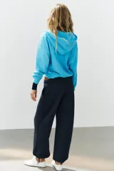 Sudadera con capucha ajustable con cordones, cierre frontal de cremallera, mangas largas, bolsillos tipo canguro y efecto lavado en color celeste.