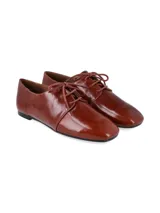 Zapato tipo oxford de cuero charolado color cognac, con cierre de cordones y suela plana.