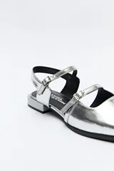 Zuecos destalonados color crema, de símil cuero, con punta cuadrada y finas tiras con hebillas ajustables. Cuentan con taco de 2,5cm de alto.