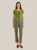 Pantalón de tiro medio y calce holgado, con diseño a rayas en tonos verde, marrón y violeta, bolsillos laterales y traseros, y cierre frontal con botón y cremallera.