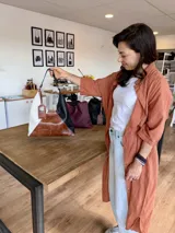 Bolso tipo hobo de cuero con diseño geométrico tricolor: blanco, marrón y negro.