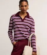 Blusa polo de manga larga confeccionada en algodón sostenible, con diseño a rayas horizontales en tonos bordó, blanco y violeta, cuello polo y escote en V.