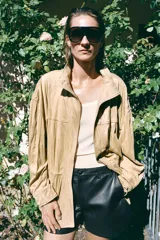 Chaqueta de efecto ante con cuello alto, manga larga y cierre frontal oculto por solapa con botones. Cuenta con bolsillos delanteros de plastrón con solapa y cintura ajustable con cordones.
