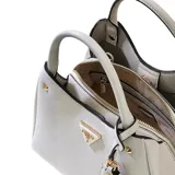 Cartera tipo bolso de mano Guess modelo Meridian II, color blanco, con textura granulada. Presenta herrajes dorados, logo triangular metálico en el frente y colgante decorativo. Incluye asas superiores fijas y correa larga ajustable extraíble.
