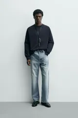 Camiseta de manga larga con cuello redondo, confeccionada en algodón compacto y pesado, con diseño de corte relajado y costuras decorativas en el cuello.