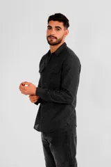Camisa negra de manga larga con dos bolsillos en el pecho y cierre con botones. Corte clásico.