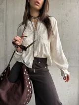 Camisa beige de manga larga, con detalles bordados en el frente y botones decorativos.