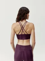 Top deportivo de sujeción media, color azul con diseño de líneas verticales en degradé. Tiene tirantes finos dobles cruzados en la espalda y logo en el frente.