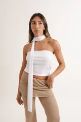 Top blanco ajustado, estilo bandeau, con un lazo largo de tela que funciona como choker y cae por el frente.