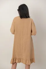 Vestido midi de lino color beige, con mangas cortas, cuello redondo, alforzas verticales en el pecho y detalle de volados en el ruedo.