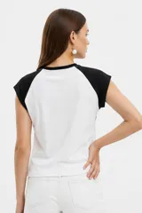 Remera al cuerpo con diseño raglán, color blanco en el torso y azul marino en las mangas cortas y el cuello. Cuenta con un estampado frontal de temática de tenis con las inscripciones "Portofino Tennis" y "Summer Italia".