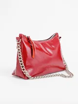 Cartera de mano de cuero charol color rojo, con diseño en forma de media luna y correa de cadena metálica plateada. Cuenta con cierre superior y tirador de cuero.