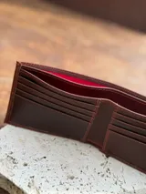 Billetera plegable de cuero color marrón rojizo, con el logo de Sierra Mora grabado en relieve en el exterior.