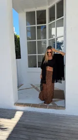 Ruana negra de tejido liviano con terminación de flecos en el ruedo y mangas amplias.