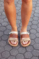 Sandalias bajas de cuero marrón y beige con tiras ajustables con hebilla.