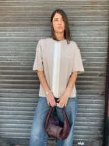 Buzo de algodón color beige, con cuello redondo, mangas cortas y tres franjas verticales en tonos blanco y beige en el frente.