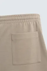 Bermuda de algodón color beige claro, corte relajado (relaxed fit), con cintura elástica ajustable mediante cordón y bolsillos laterales y trasero de plastrón.
