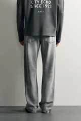 Jeans flare fit de denim de algodón en color gris con efecto lavado. Presentan diseño de cinco bolsillos, tiro medio y cierre frontal con cremallera y botón.