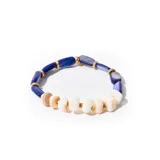 Pulsera elástica con cuentas de piedra azul, cuentas de piedra blanca y detalles dorados.