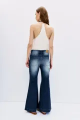 Pantalón de jean tiro medio, color azul oscuro con efecto desgastado y bigotes. Corte ajustado en cintura y cadera, con pierna acampanada desde la rodilla hasta el tobillo.