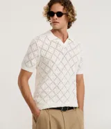 Camisa polo de manga corta con diseño de tejido calado tipo crochet y textura de rombos. Presenta cuello polo clásico y terminaciones en tejido acanalado.