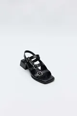 Sandalias de taco bajo cuadrado color negro con textura efecto cocodrilo, punta cuadrada y múltiples tiras cruzadas en el empeine con hebillas metálicas plateadas.